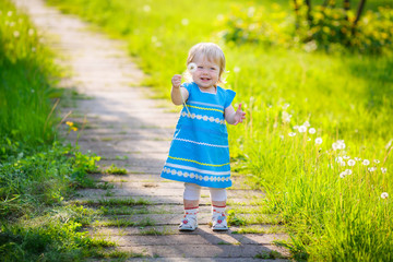 Adorable little girl blowing on white dandelion in the park