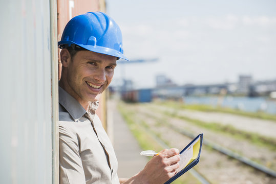 Portrait of man with blue safety helmet checking cargo containers