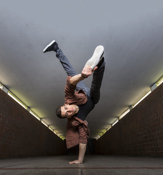 Young breakdancer performing a handstand in underpass