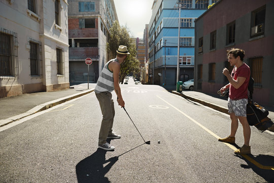 Two friends playing urban golf in the city