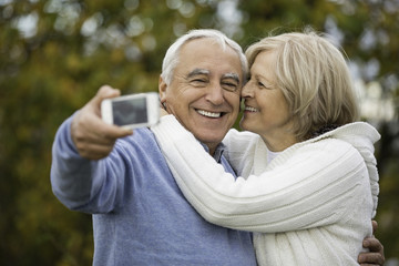 Portrait of happy senior couple taking self-portrait with smartphone