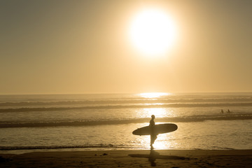 surfer walks in the sunset