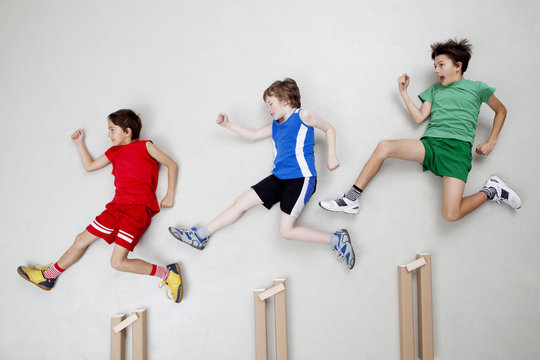 Boys jumping over hurdles