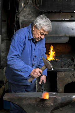 Germany, Bavaria, Josefsthal, blacksmith working on billhook at historic blacksmith's shop