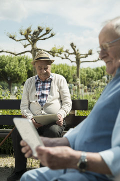 Germany, Worms, Two old men using tablet computers in the park
