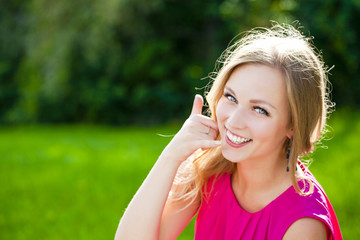 Beautiful happy blonde woman making a call me gesture