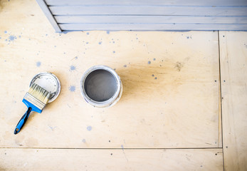 open jar with gray paint and a brush on the floor