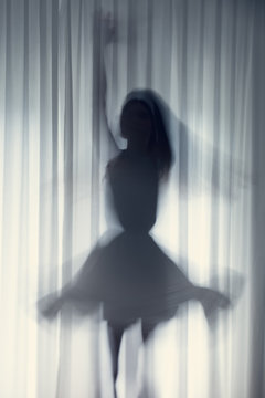 Silhouette Of A Young Woman Dancing In Front Of A White Curtain