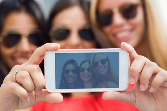 Three friends taking photos with a smartphone