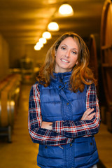 cheerful young woman oenologist tasting wine in cellar