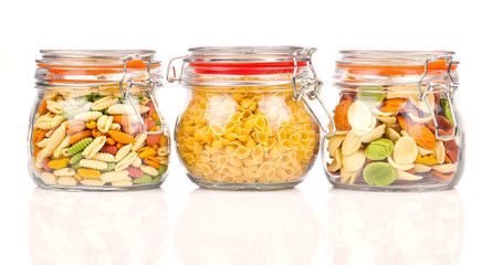 the various raw pasta in a glass jar, isolated on white backgrou