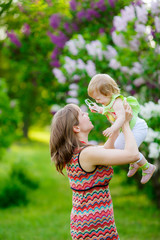 Obraz premium happy mother with baby garden of blooming lilacs. 