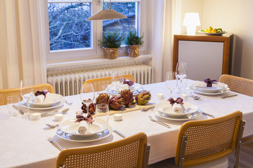 Place settings and decoration with artichokes on festive laid table in the evening