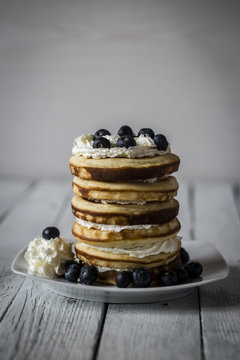 Stack of pancakes and blueberries on dish, studio shot