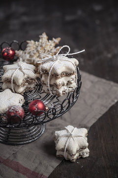 With powdered sugar sprinkled star-shaped cinnamon cookies and red Christmas baubles on cake stand