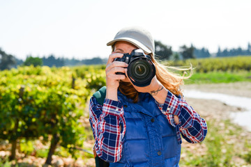 cheerful young woman hiking and taking pictures with camera