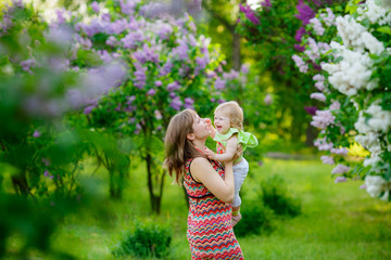 happy mother with baby garden of blooming lilacs. 