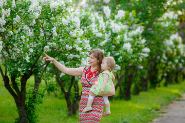 happy mother with baby garden of blooming lilacs. 