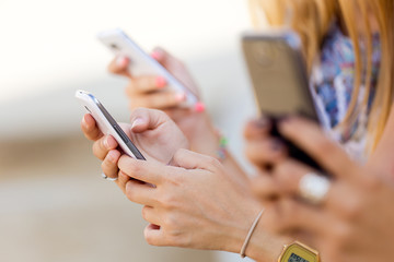 Three girls chatting with their smartphones at the park