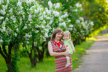 happy mother with baby garden of blooming lilacs. 