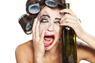 young drunk woman with curlers crying next to a bottle of wine