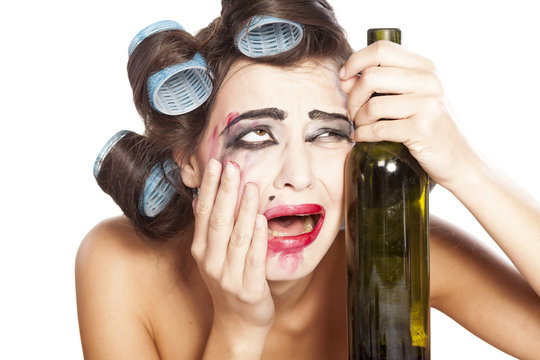 young drunk woman with curlers crying next to a bottle of wine