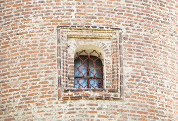 window with forged bars in the historic tower built of red brick