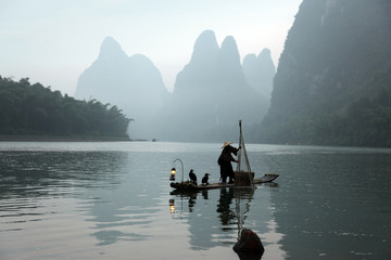 Chinese man fishing with cormorants birds in Yangshuo, Guangxi r