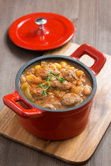 delicious vegetable stew with sausages in a pan on wooden board