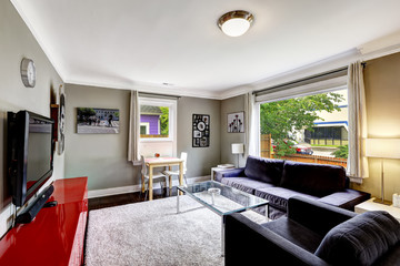 Light grey living room with bright red cabinet and black furnitu
