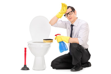 Exhausted young man cleaning a toilet