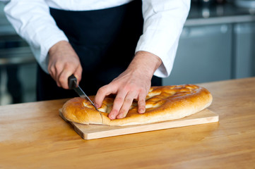 Male chef cutting bread loaf