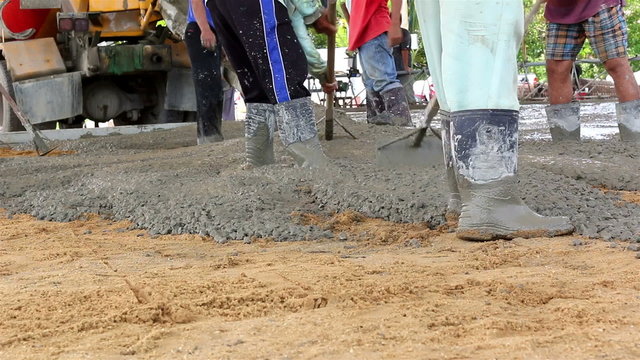 Construction workers spreading freshly poured concrete mix
