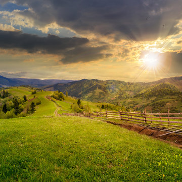 fence on hillside meadow in mountain at sunset