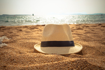 straw fedora hat on sandy beach