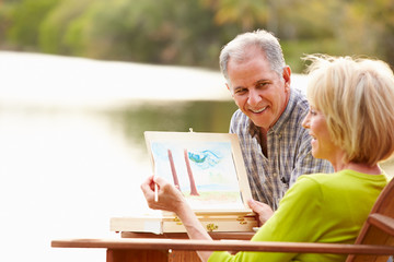 Senior Couple Sitting At Outdoor Table Painting Landscape