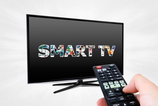 Hand with remote control aiming modern Smart TV device