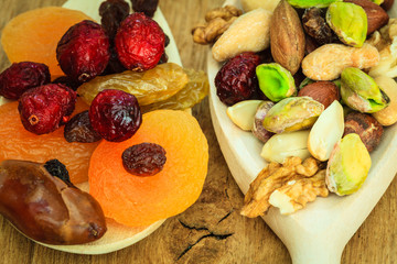 Varieties of dried fruits and nuts on wooden spoons.