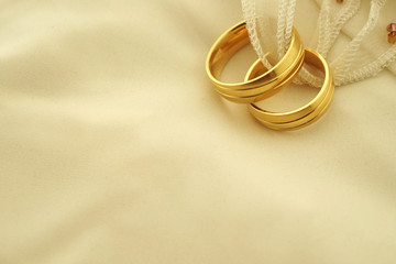 Wedding rings on cream coloured ring pillow copy space