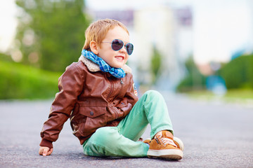cute stylish boy in leather jacket sitting on the road