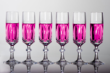 bicchieri cristallo in fila frontale con riflessi liquido rosa