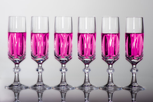 bicchieri cristallo in fila frontale con riflessi liquido rosa