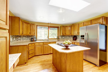 Golden tones kitchen interior with island and skylight