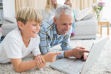 Obraz premium Father and son using laptop on the floor