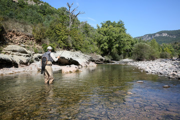 Fly fisherman flyfishing in river