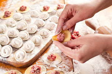 Fototapeta na wymiar Dumplings. Dough with meat filling on the cook's hands.
