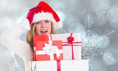 Composite image of festive blonde holding pile of gifts