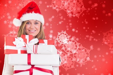 Composite image of festive blonde holding pile of gifts
