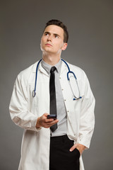 Thinking doctor holding telephone