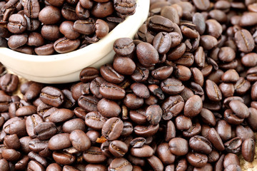Coffee beans placed on bag sack and white cup.